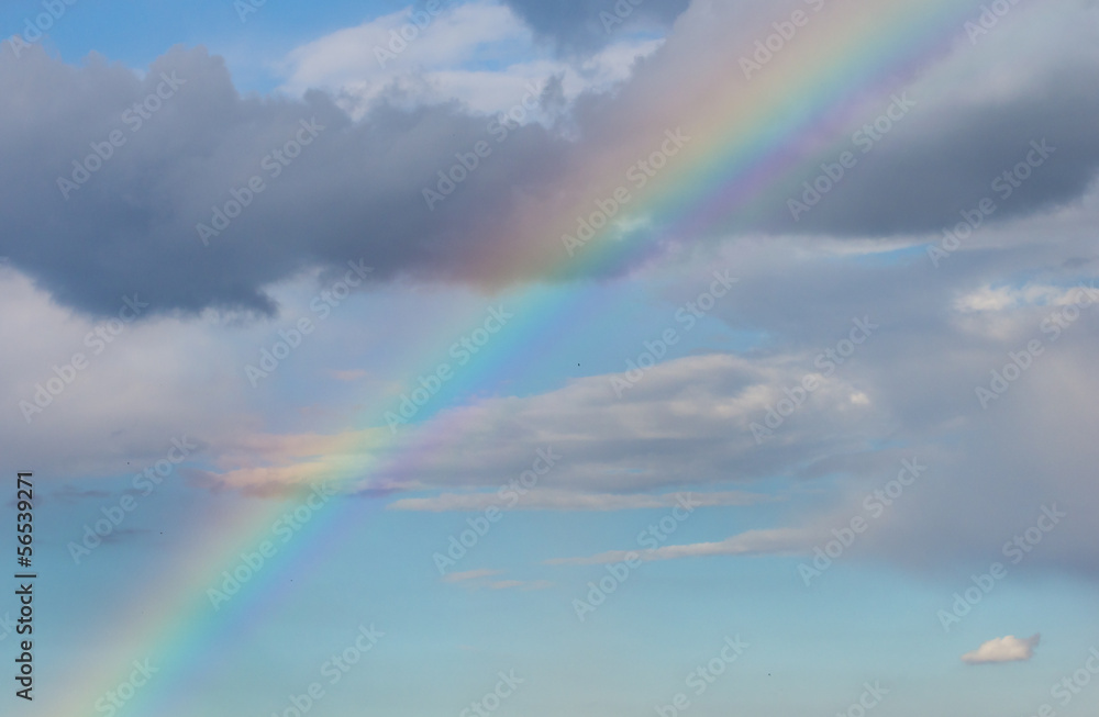 Rainbow on blue sky with clouds