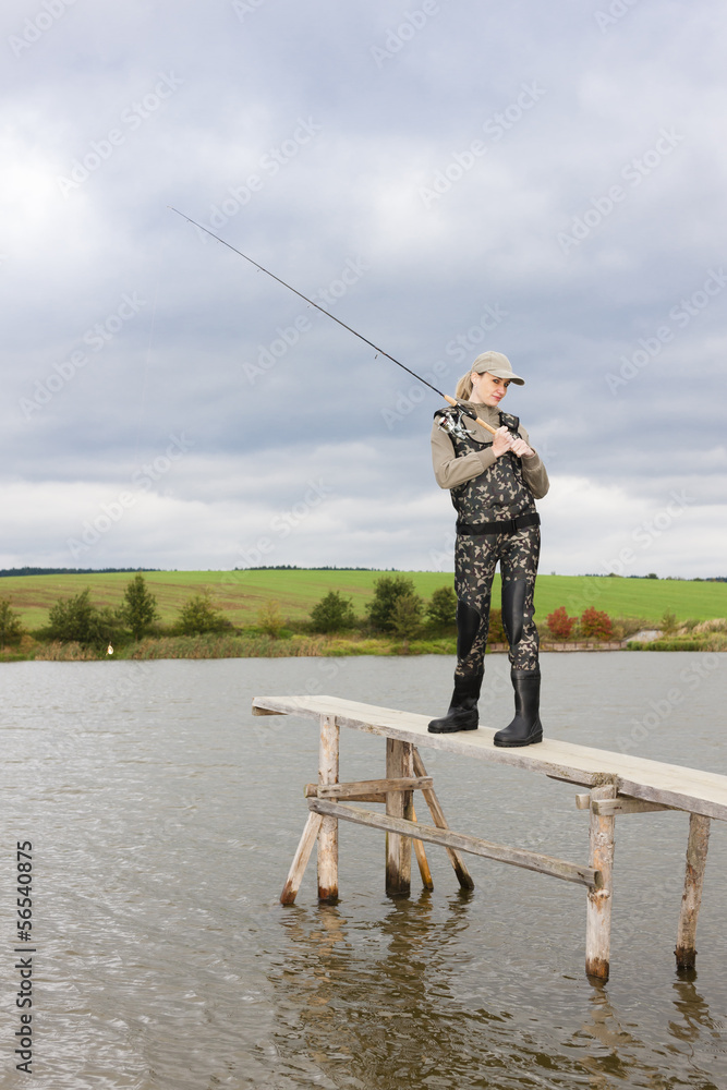 woman fishing on pier at pond woman fishing on pier at pond