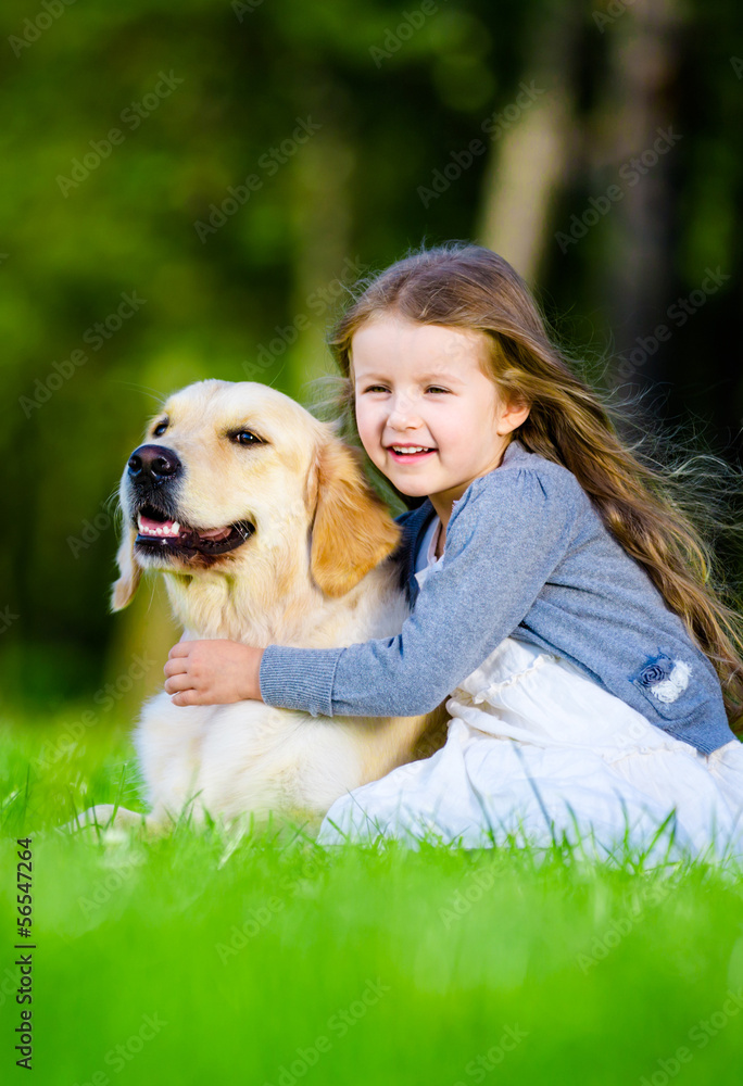 Little girl sitting on the grass with labrador 
