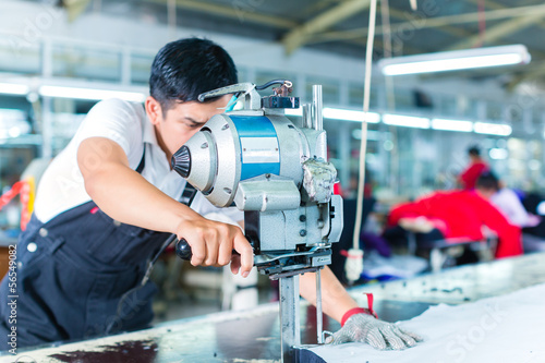 Canvas Print Asian worker using a machine in a factory