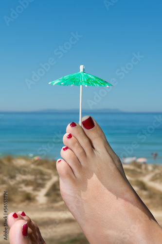 feet relaxing at the beach cocktail umbrella