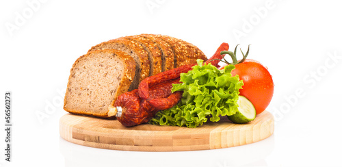 bread and smoked sausages on wooden plate isolated on white