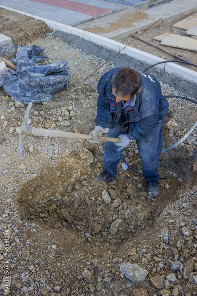 Construction Worker Digging a Deep Underground Hole with a pick Construction Worker Digging a Deep Underground Hole with a pick