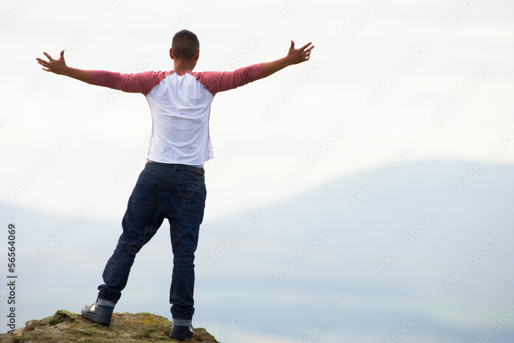 Young Man Standing On Rock With Outstretched Arms Young Man Standing On Rock With Outstretched Arms
