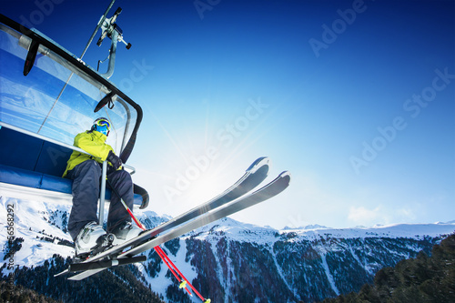Skier siting on ski-lift - lift at sunny day and mountain