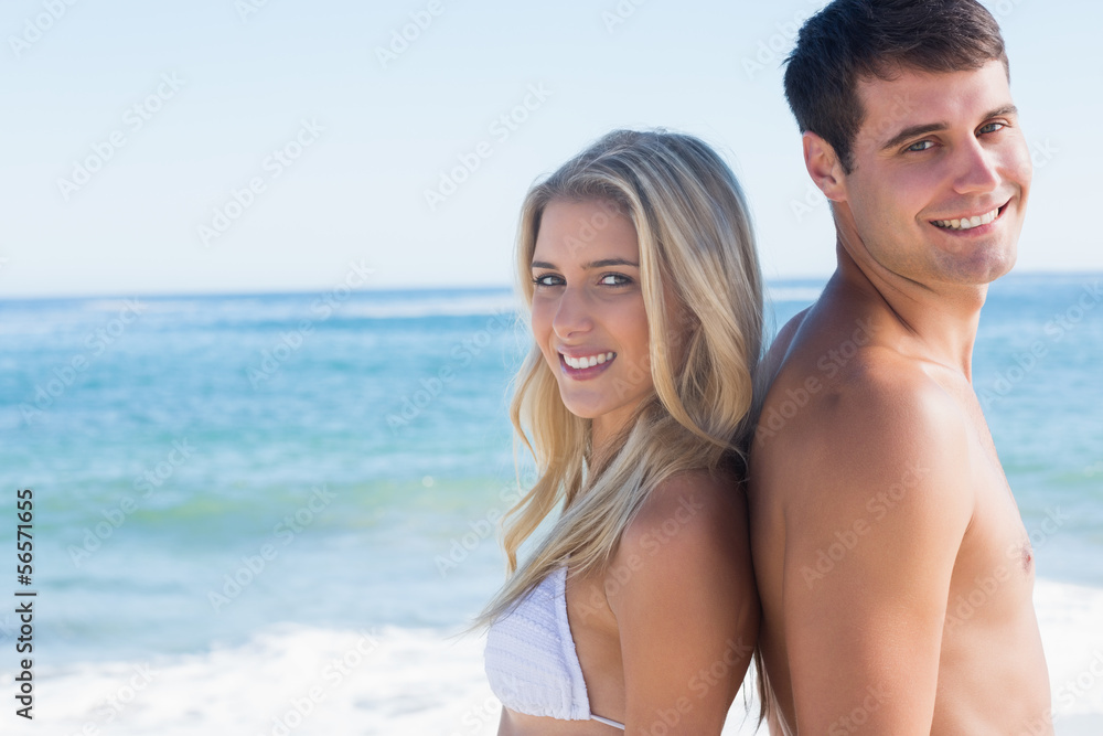 Young smiling couple standing back to back Young smiling couple standing back to back