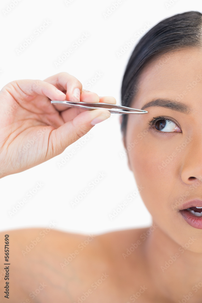 Half face of apprehensive natural woman using tweezers