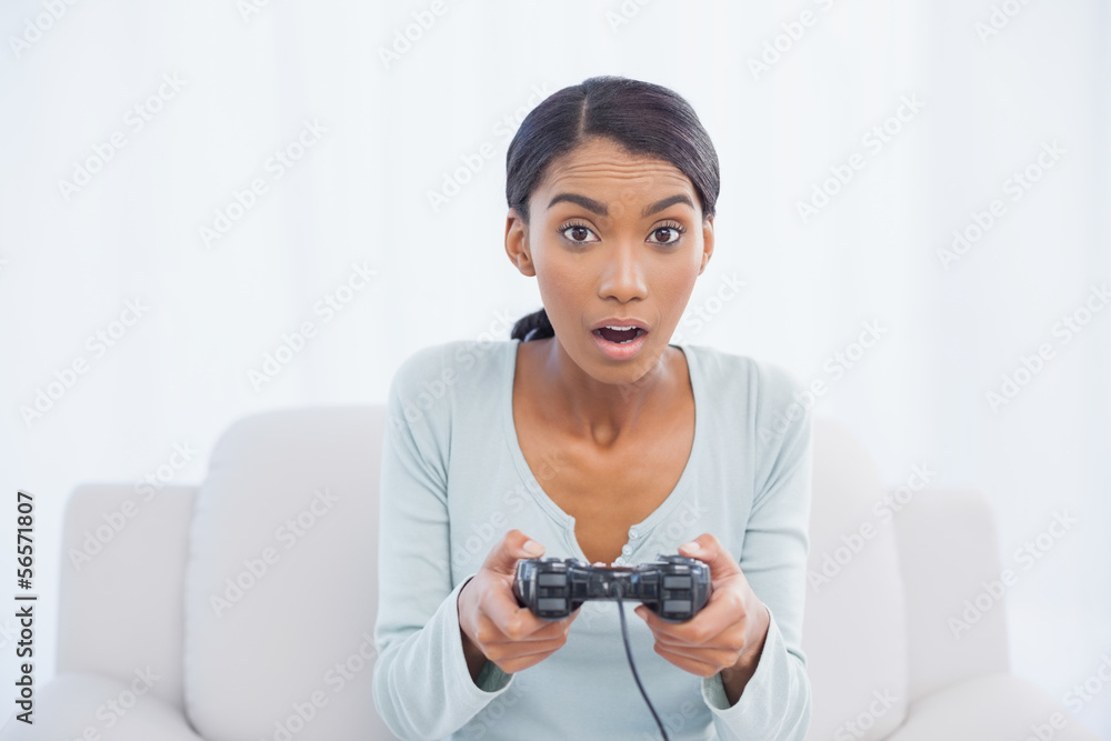 Shocked woman sitting on sofa playing video games Shocked woman sitting on sofa playing video games