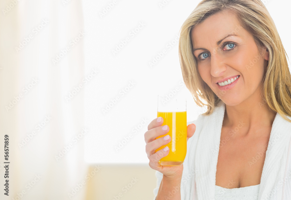 Satisfied woman looking at camera enjoying a glass of orange jui Satisfied woman looking at camera enjoying a glass of orange jui