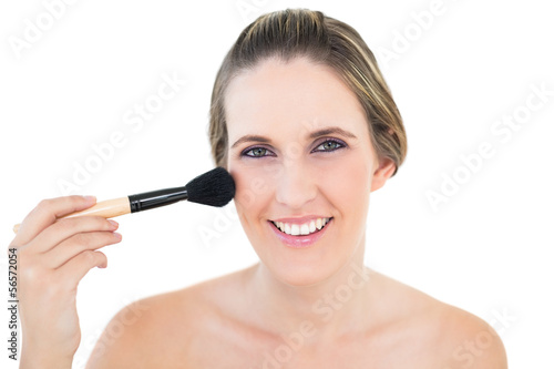 Cheerful woman using blusher brush