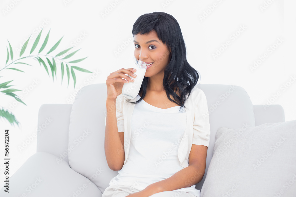Charming black haired woman in white clothes drinking a glass of Charming black haired woman in white clothes drinking a glass of