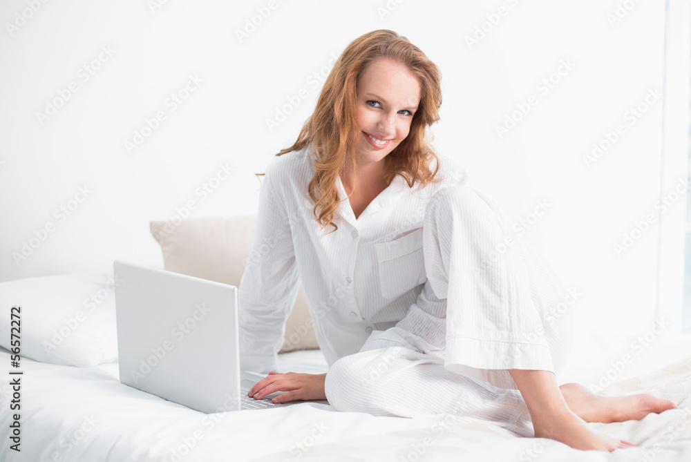 Content pretty woman using a laptop sitting on her bed Content pretty woman using a laptop sitting on her bed