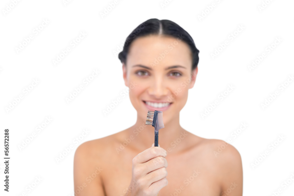 Relaxed young model holding eyebrow brush in front of her Relaxed young model holding eyebrow brush in front of her