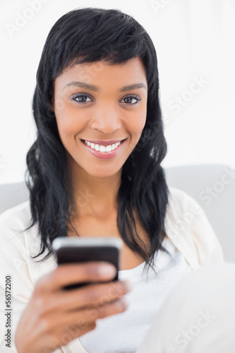 Natural black haired woman in white clothes holding a mobile pho