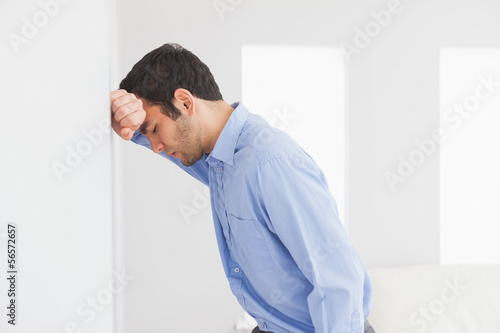 Sad man leaning his head against a wall