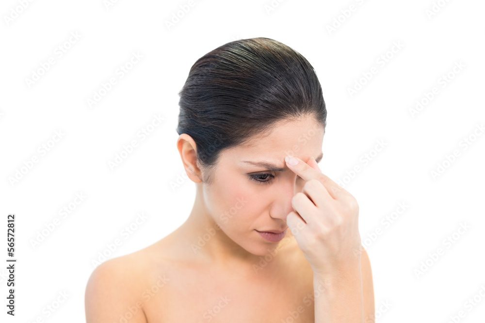Frowning brunette with a headache pinching her nose Frowning brunette with a headache pinching her nose
