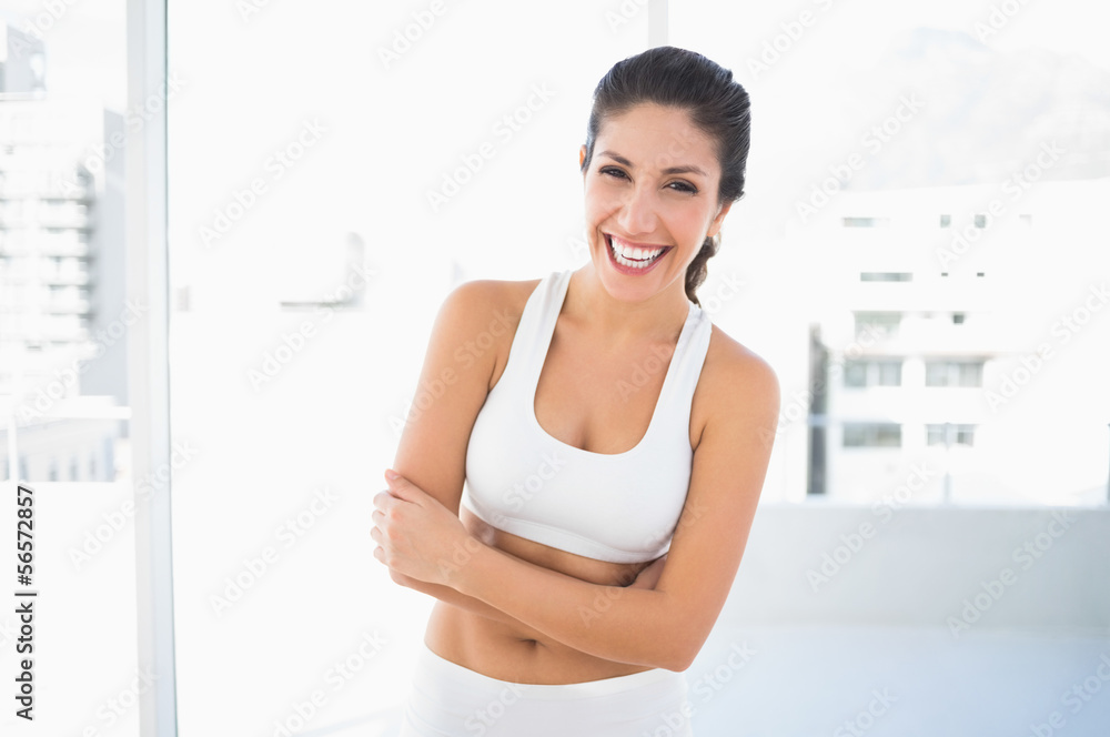 Fit laughing woman in sportswear with arms crossed looking at ca Fit laughing woman in sportswear with arms crossed looking at ca