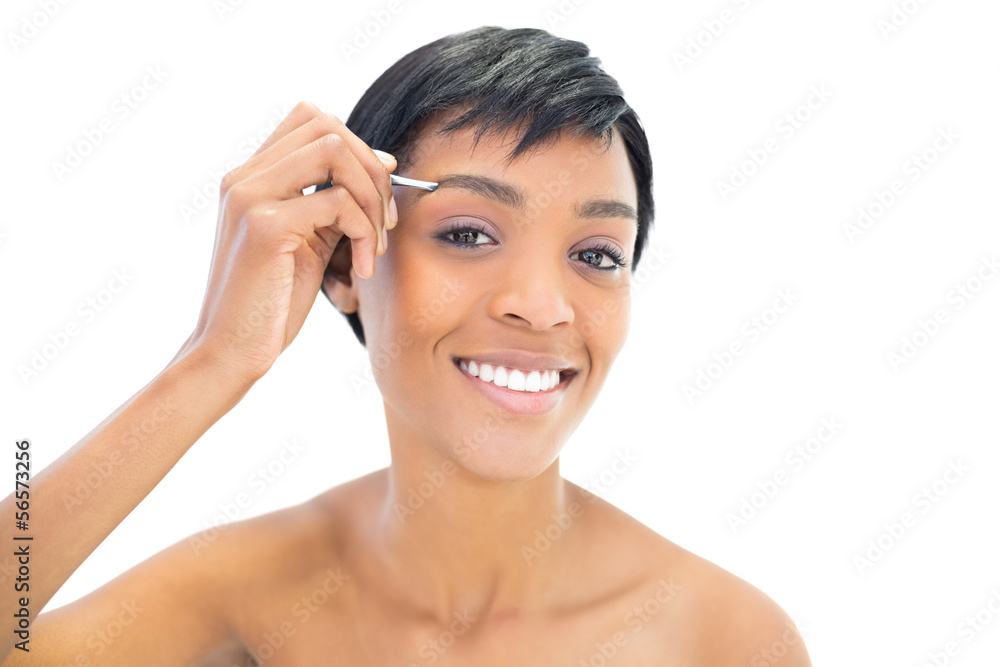 Content black haired woman plucking her eyebrows Content black haired woman plucking her eyebrows
