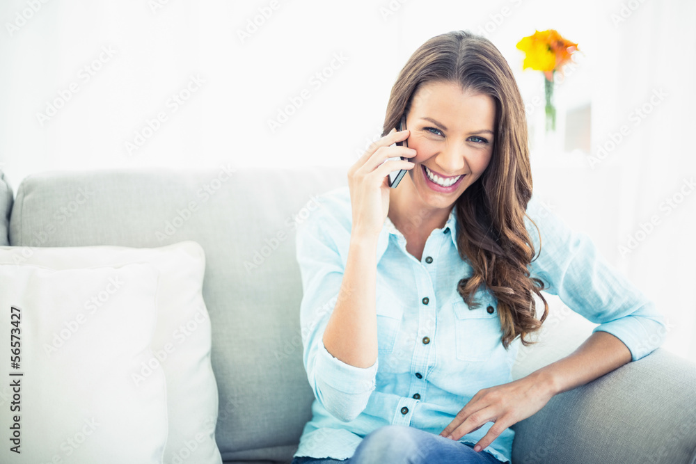 Attractive model sitting on cosy couch having a phone call Attractive model sitting on cosy couch having a phone call