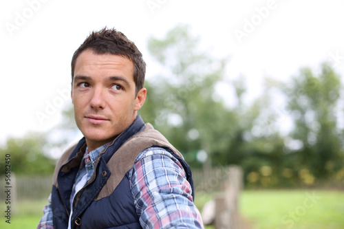 Man in countryside leaning on fence