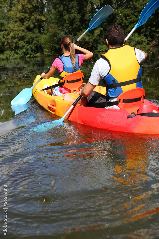Couple riding canoe in river Couple riding canoe in river