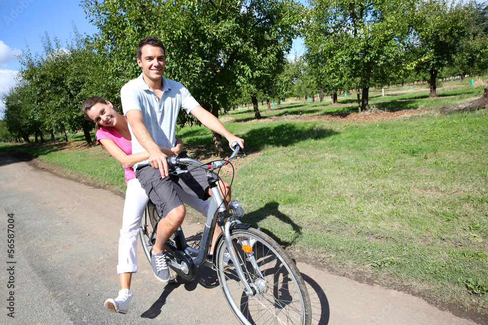 Cheerful young couple riding bikes in countryside