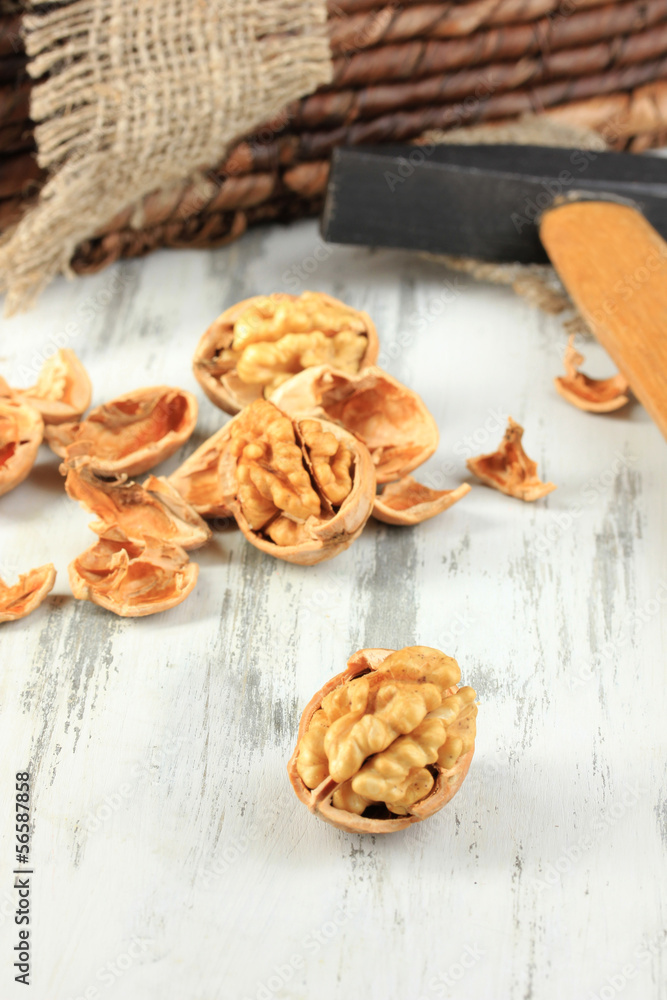 Broken walnuts with hammer on wooden table close-up Broken walnuts with hammer on wooden table close-up