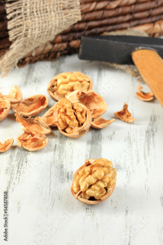 Broken walnuts with hammer on wooden table close-up