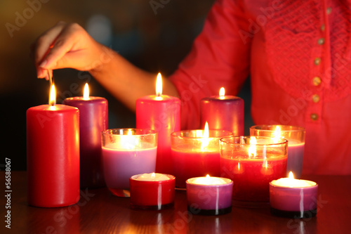 Woman lights candles on bright background