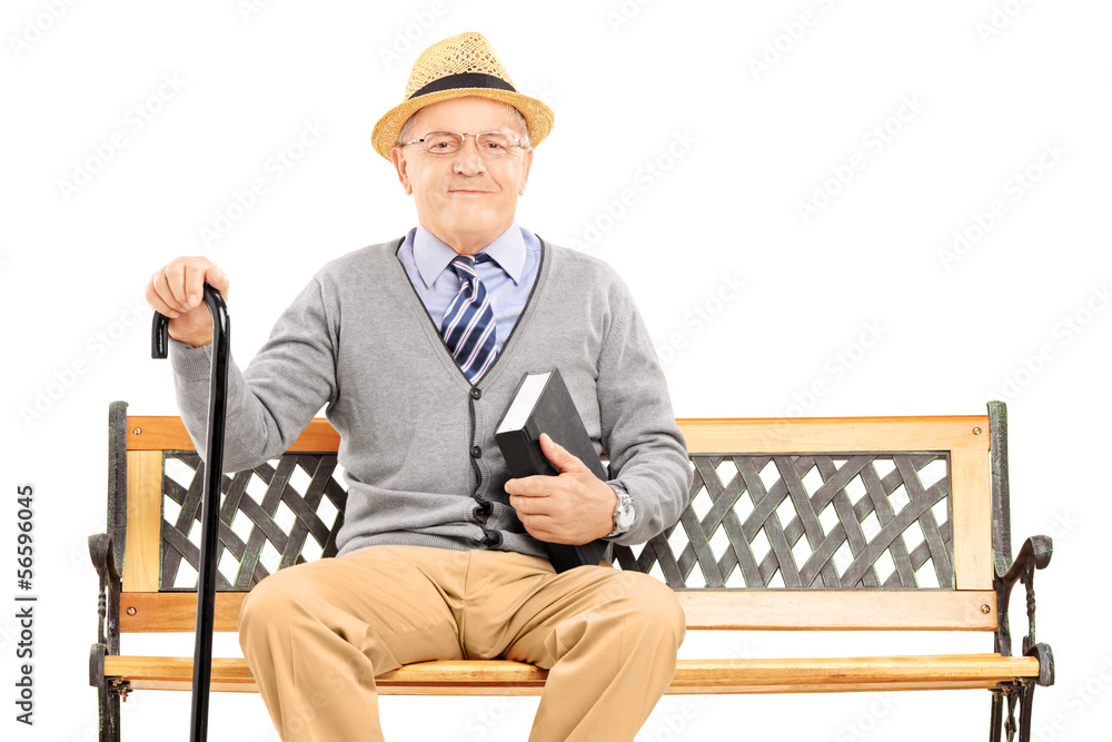 Senior man sitting on a wooden bench with book