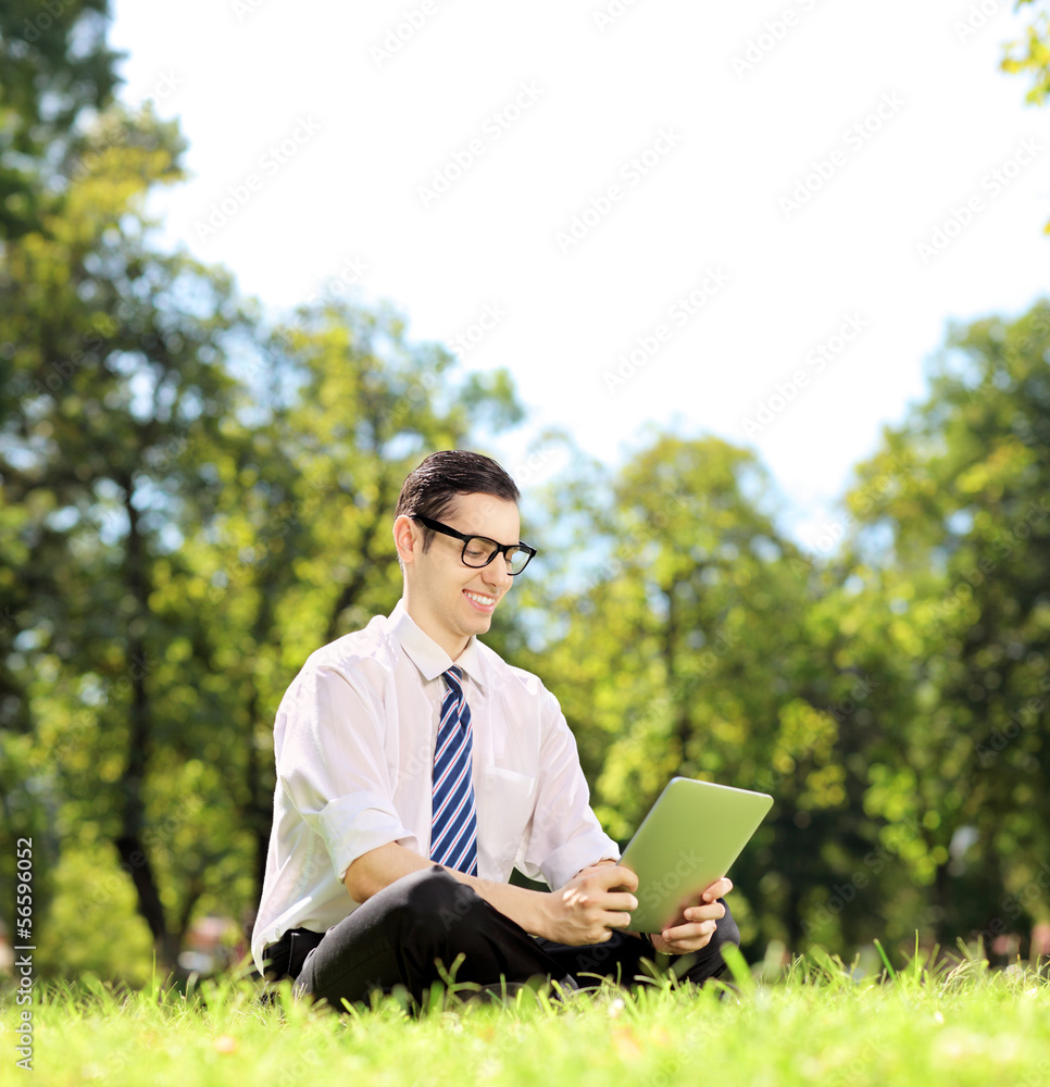 Young businessman working on a tablet in a park