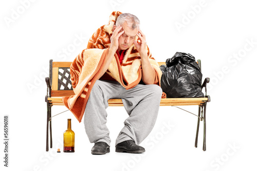 Disappointed homeless mature man sitting on a wooden bench