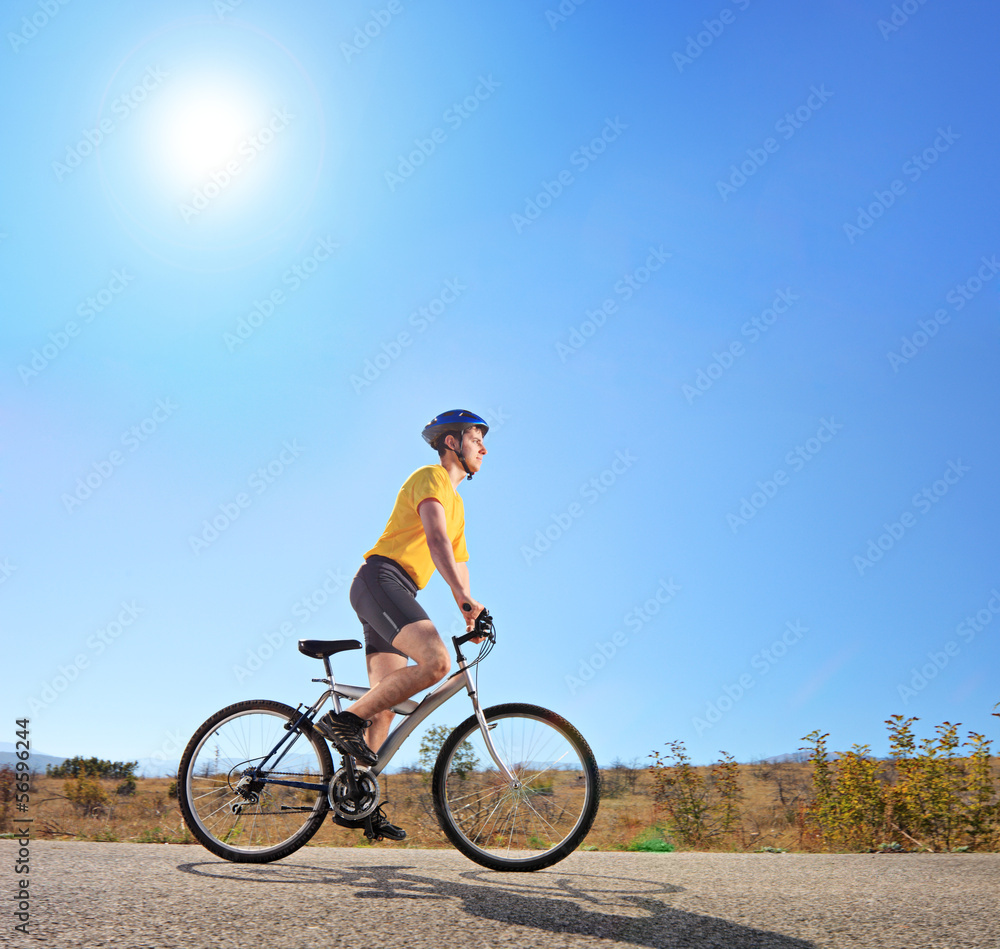 Young male with helmet riding a bike on a sunny day