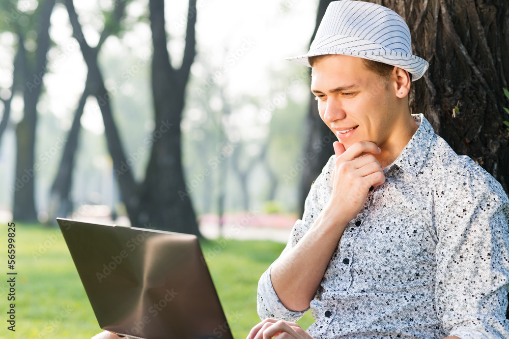 Fototapeta premium young man working in the park with a laptop