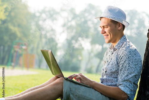young man working in the park with a laptop