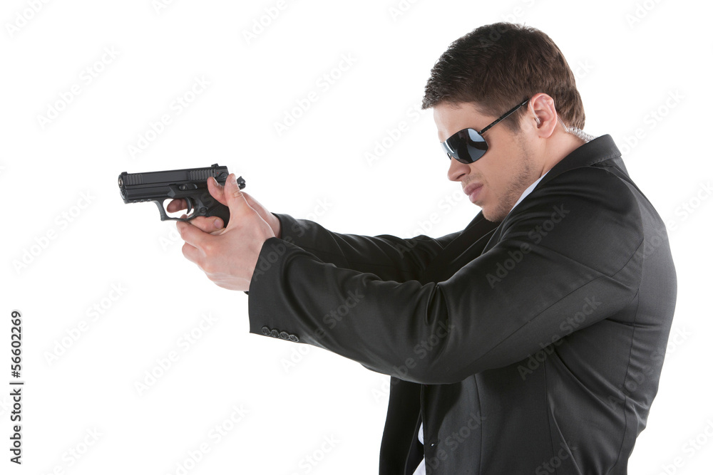 Bodyguard. Side view of confident young man holding gun and aimi Bodyguard. Side view of confident young man holding gun and aimi