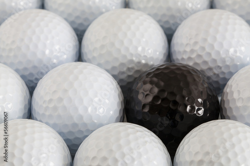 White golf balls and one black ball
