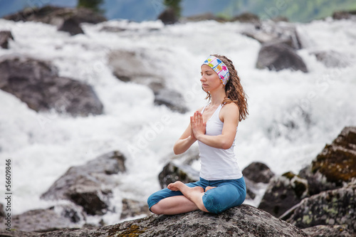 Young woman is practicing yoga at mountain river