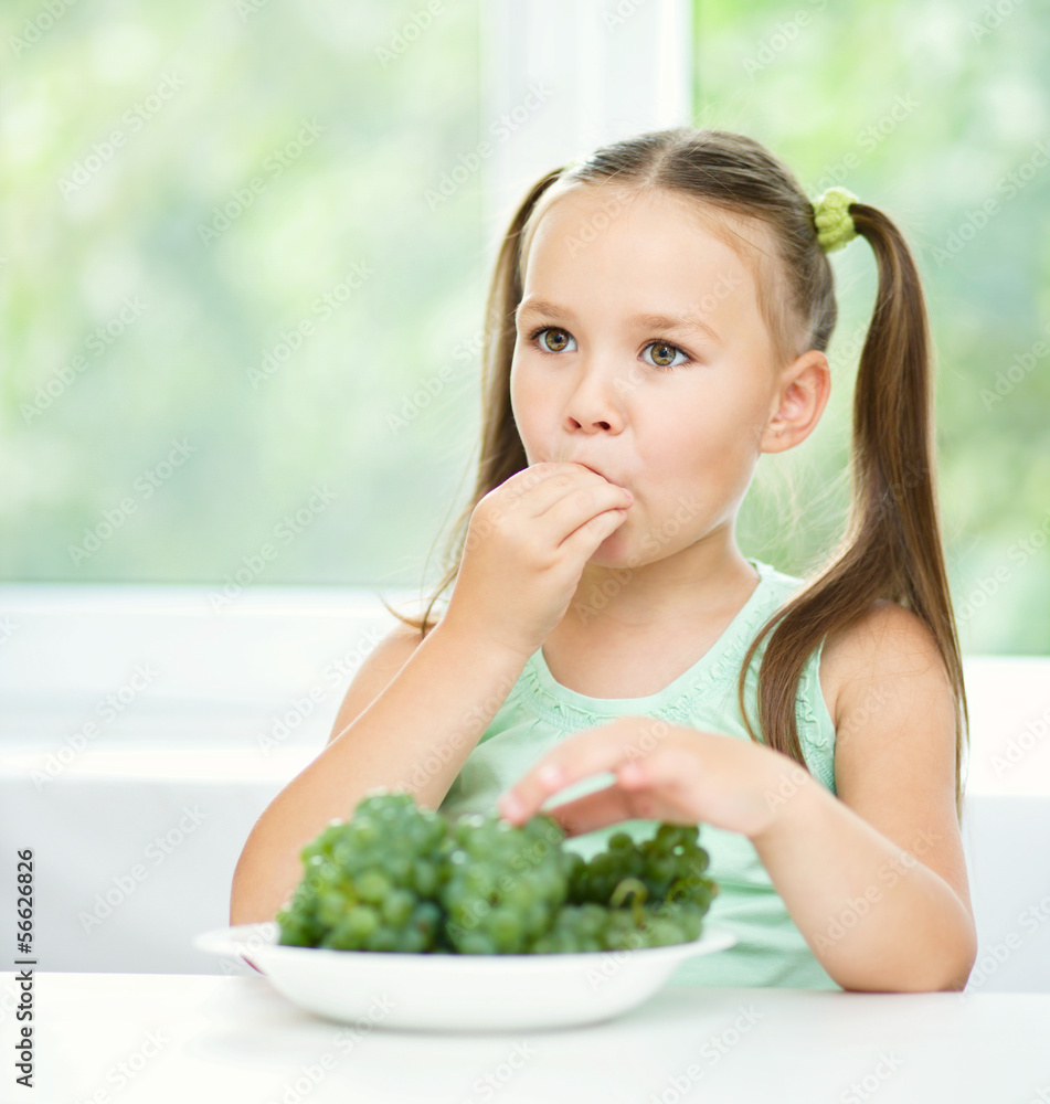 Cute little girl is eating green grapes Cute little girl is eating green grapes