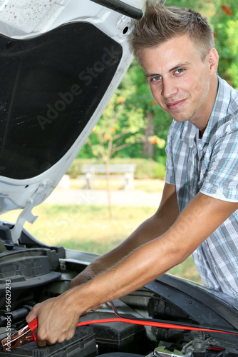 Young driver uses battery jumper cables to charge dead battery