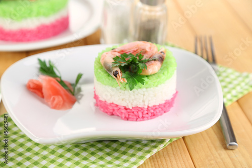Colored rice on plates on napkin on wooden table
