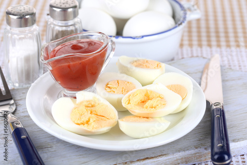 Boiled eggs on plate on wooden board on tablecloth