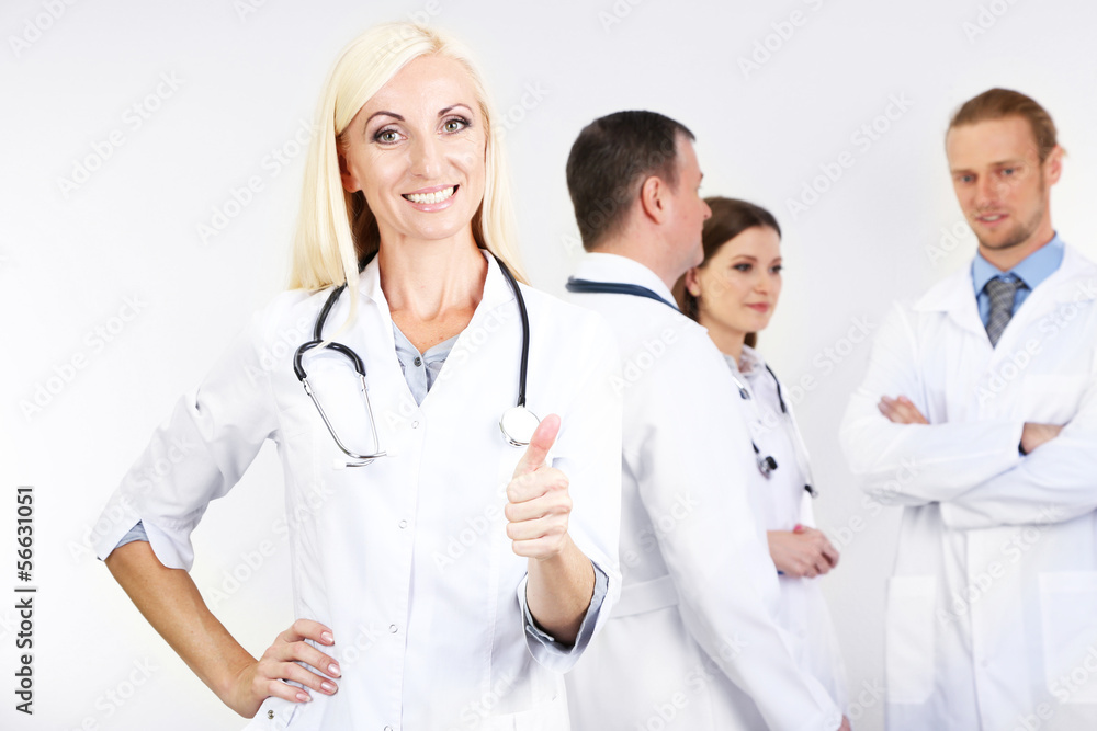 Doctor standing in front of coworkers on grey background Doctor standing in front of coworkers on grey background