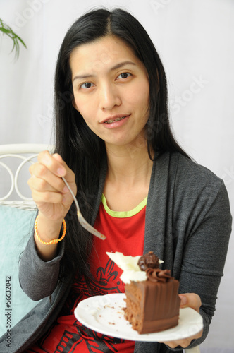 Asian woman showing chocolate cake, relaxing