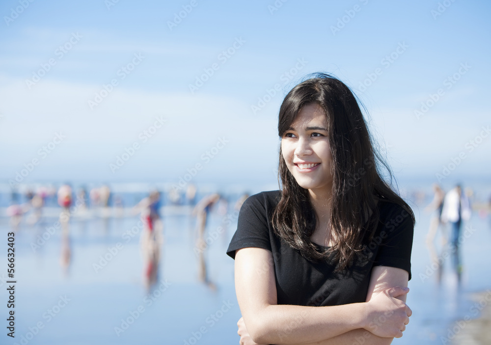 Beautiful biracial young woman or teen walking along beach by Pa