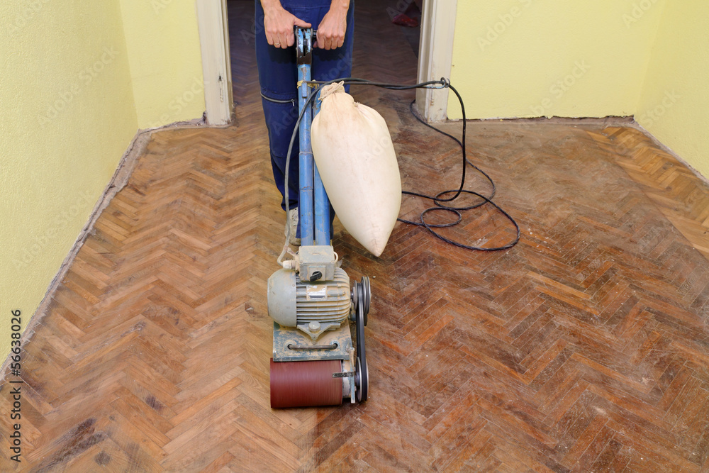 Worker polishing parquet floor with grinding machine - obrazy, fototapety, plakaty 