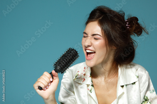 Cheerful attractive teen girl sing song holding comb like a micr photo