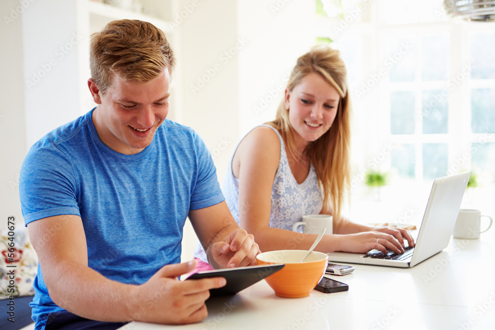 Teenagers Having Breakfast Using Laptop And Tablet Computer Teenagers Having Breakfast Using Laptop And Tablet Computer