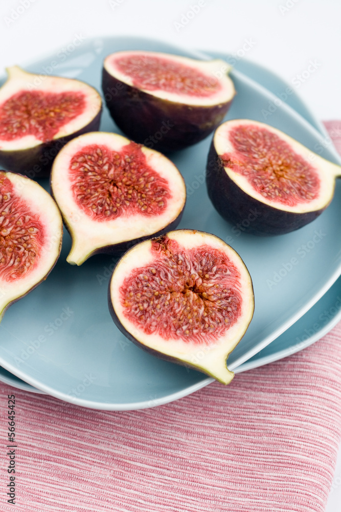 Ripe figs lying on a blue plate on a pink napkin Ripe figs lying on a blue plate on a pink napkin