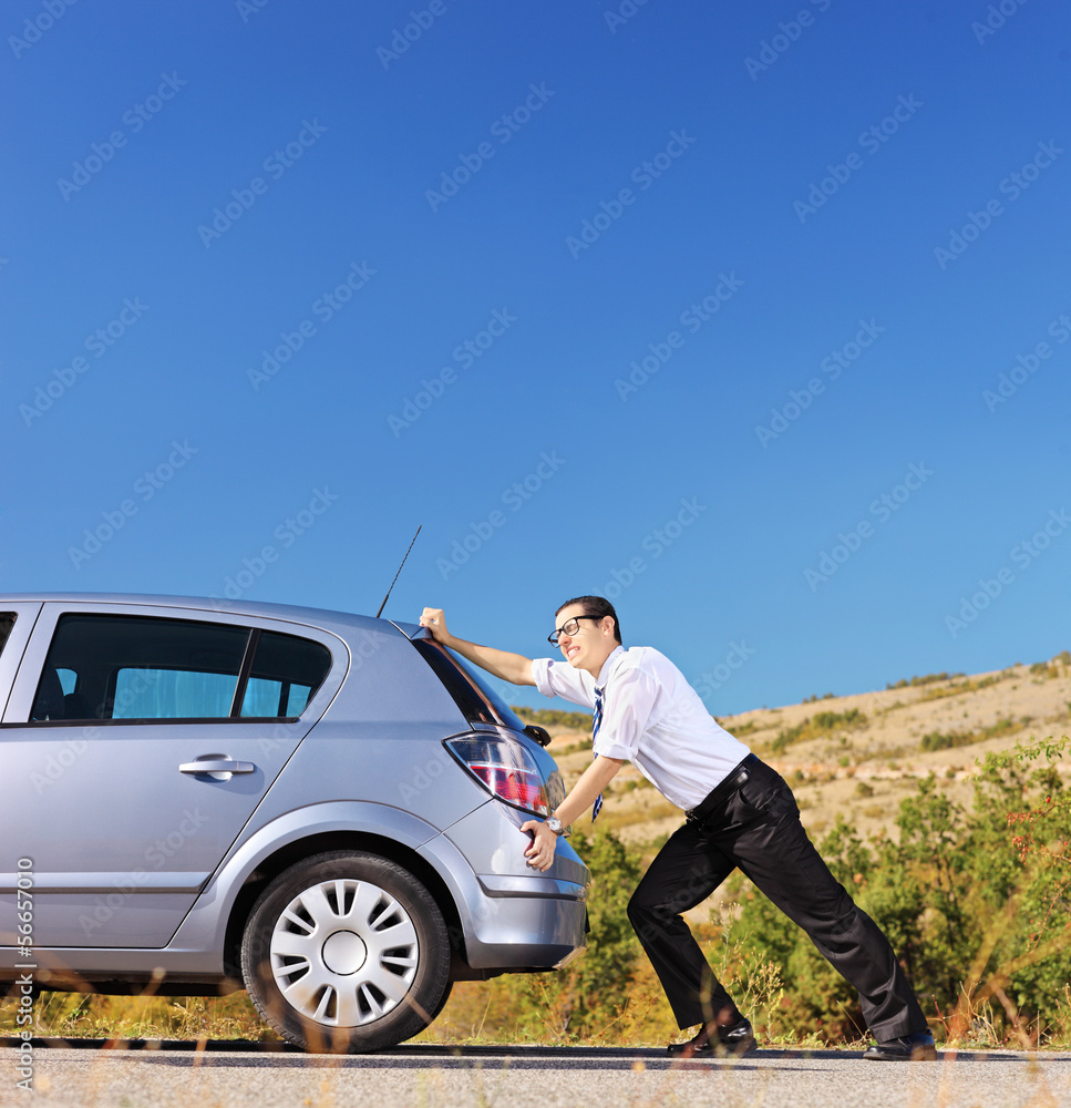 Young businessman pushing his car with empty fuel tank